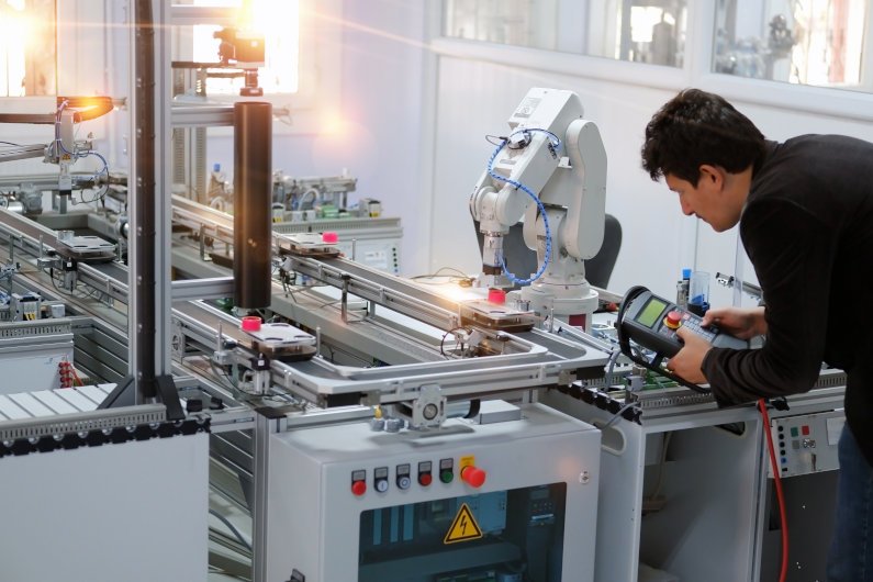 man controls robotic arm production line 795
